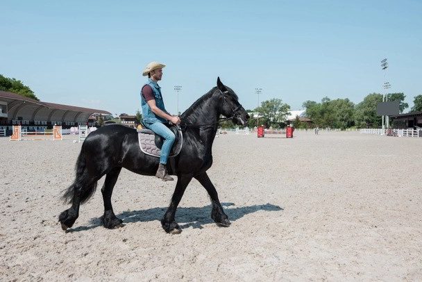 hombre usar un sombrero de vaquero mientras se monta a caballo